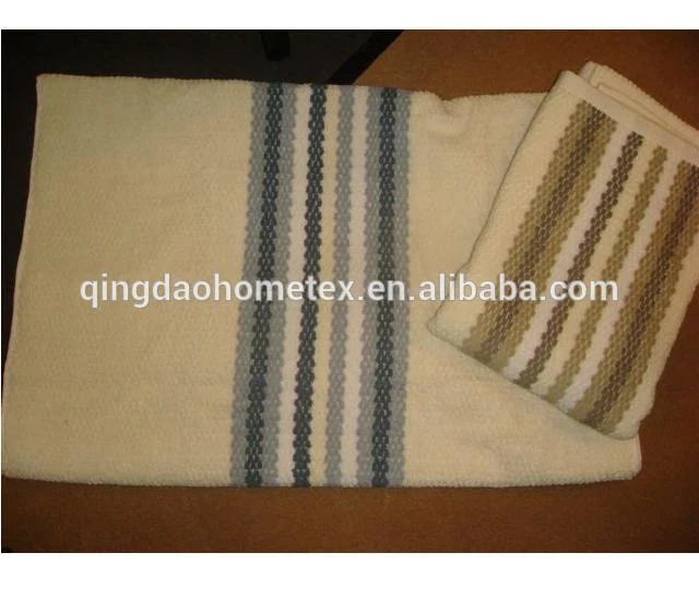 Two cream towels with stripes, one laid flat with blue-gray bands and one folded with brown bands