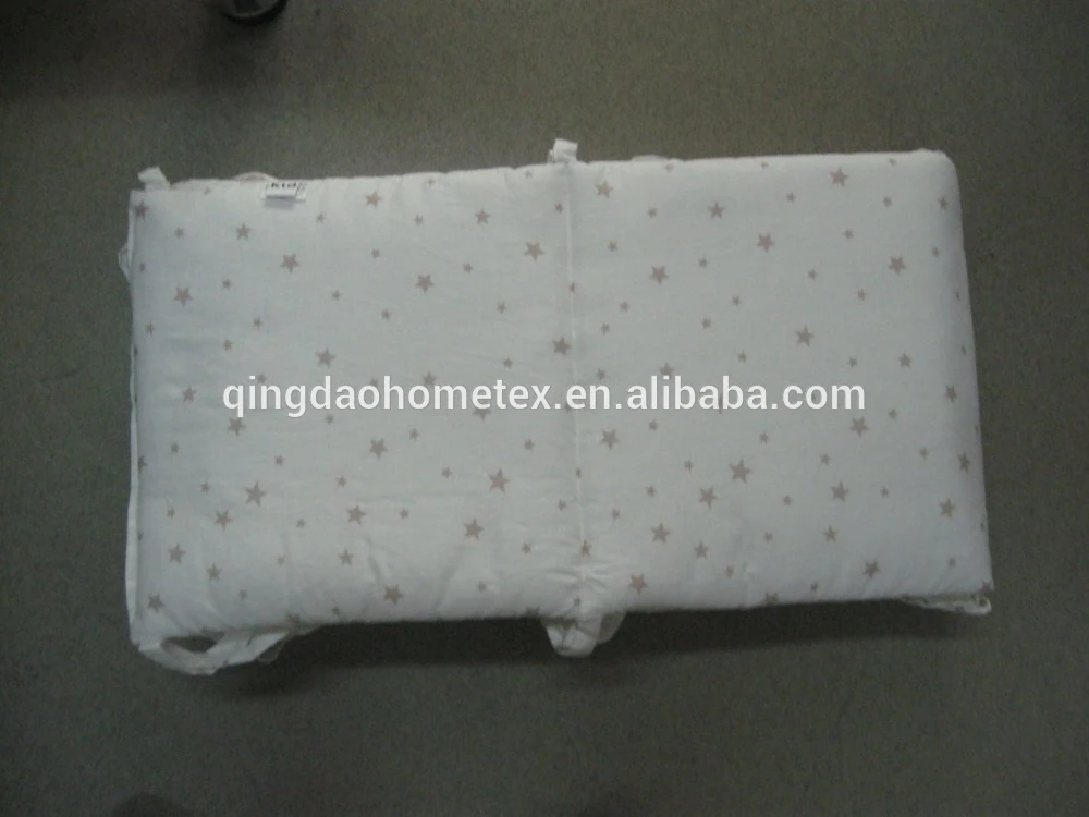 White quilted fabric pad with star print lying flat on a gray floor, overlaid with Alibaba URL watermark text