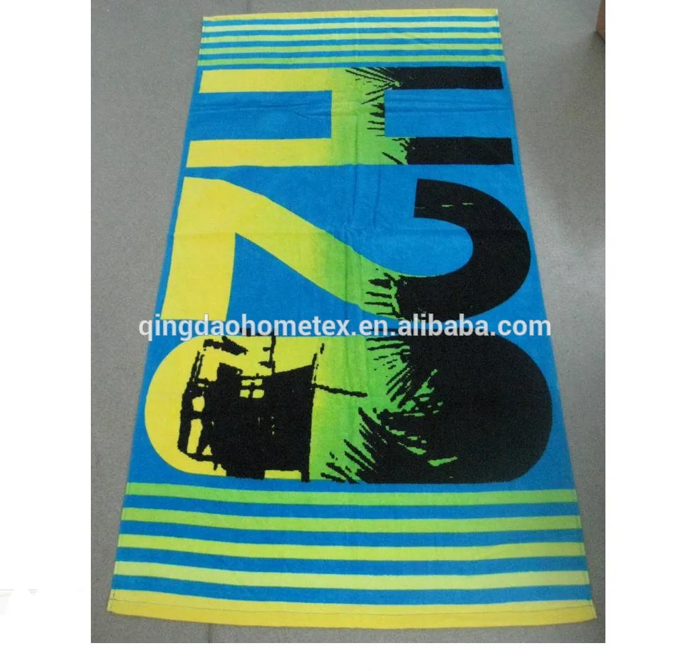 Blue printed beach towel with large H2O design and yellow-green striped borders laid on a gray floor