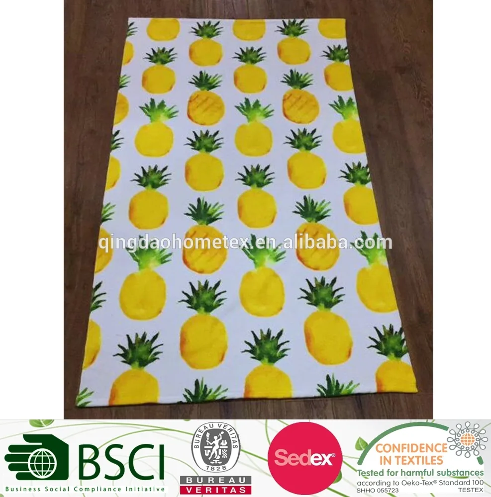 Rectangular fabric with yellow pineapple print laid flat on a wooden floor