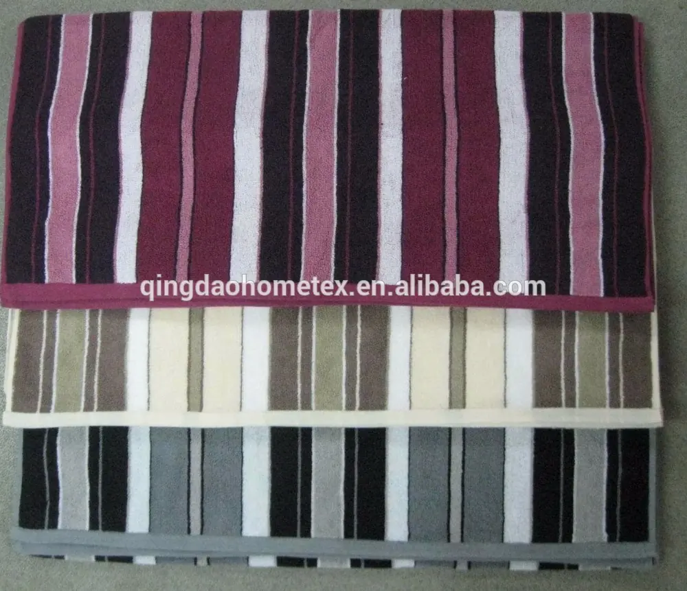 Three folded striped towels in burgundy, beige and grey stacked on a grey floor