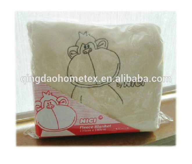 Plastic-wrapped fleece blanket with monkey illustration on NICI-branded red packaging, resting against a window