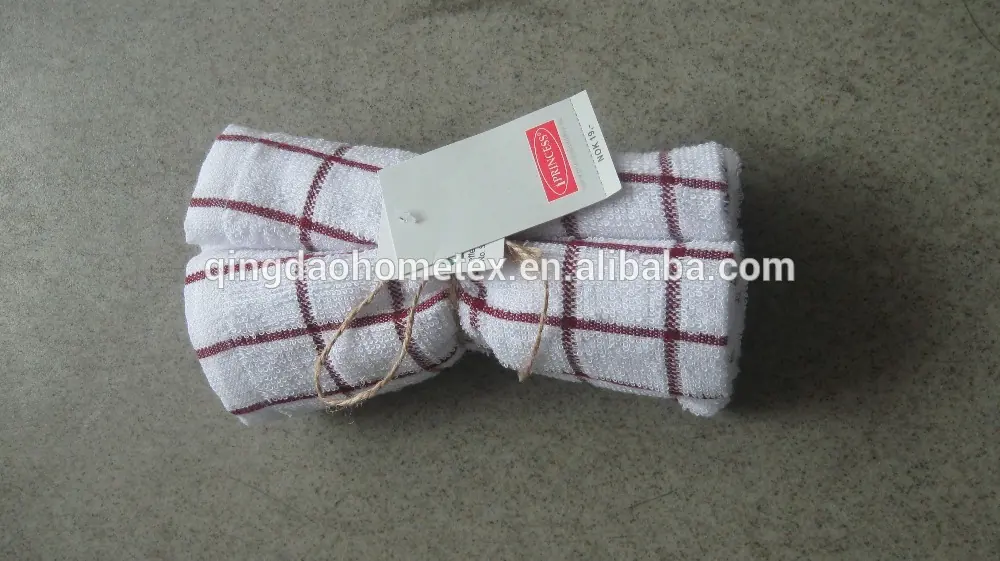 Rolled white kitchen towel with red grid pattern and hang tag on concrete floor
