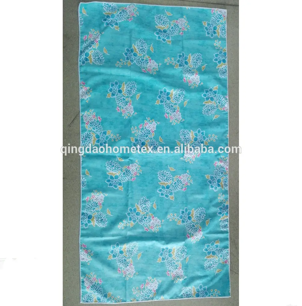 Turquoise towel with blue and pink floral print lying flat on a concrete floor