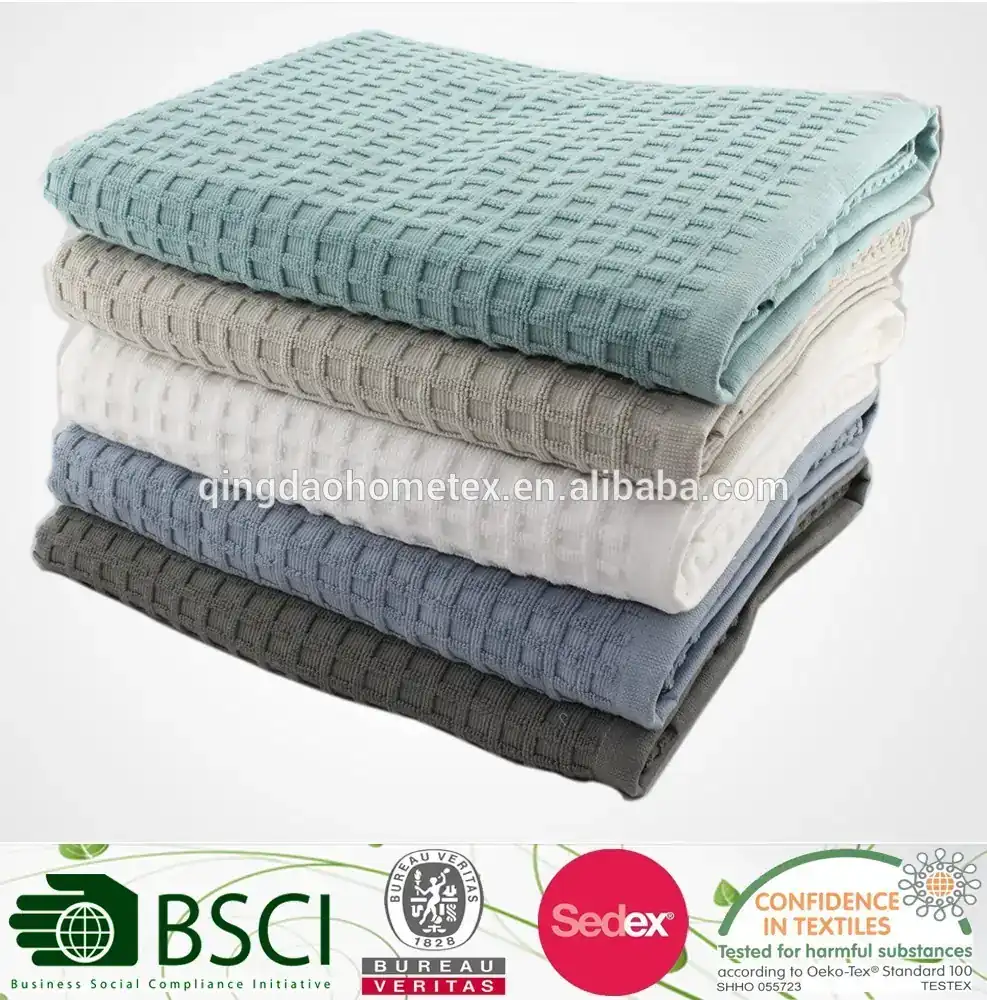 Stack of folded waffle-weave blankets in blue, gray, white, and teal on a white background