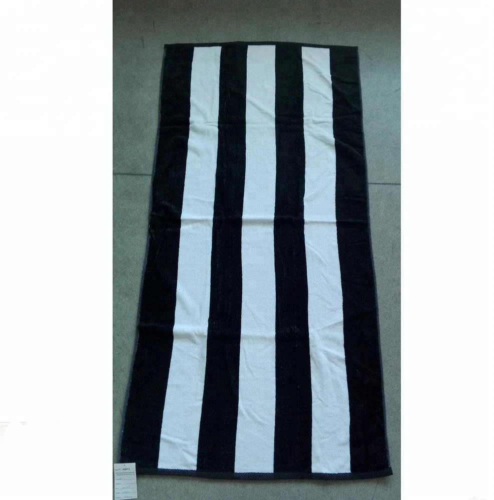 Black and white striped beach towel laid flat on a grey floor