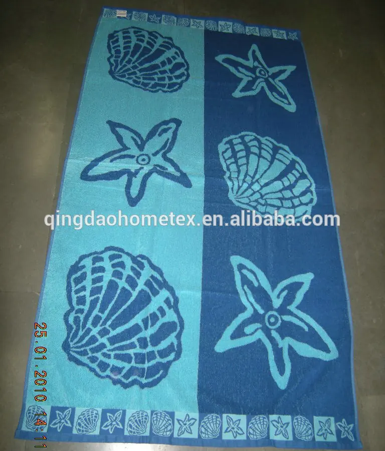 Blue and teal beach towel with printed seashell and starfish patterns, laid flat on a floor