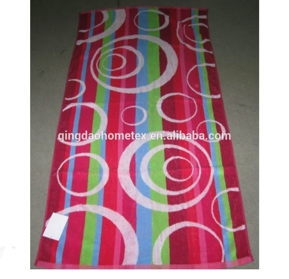 Colorful striped beach towel with white circle patterns in pink, green, and blue, laid flat