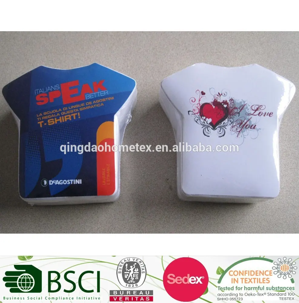 Two t-shirt-shaped packaged items on a gray surface, one printed in blue with text, one white with heart design