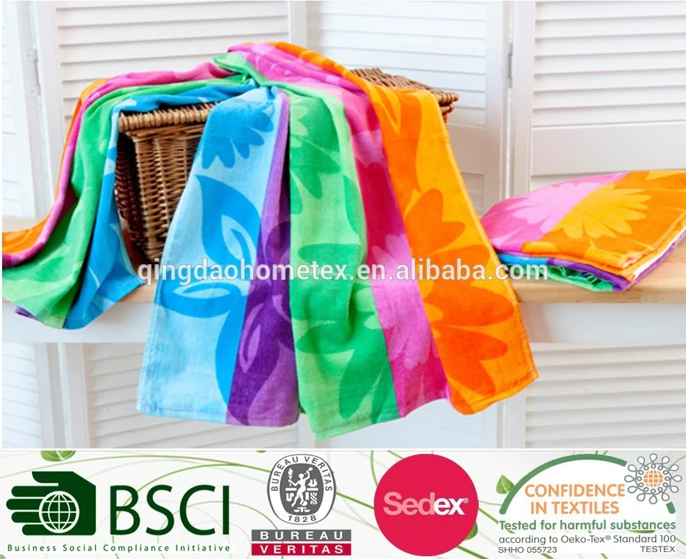 Colorful floral-patterned beach towels draped over a wicker basket with certification logos overlaid below