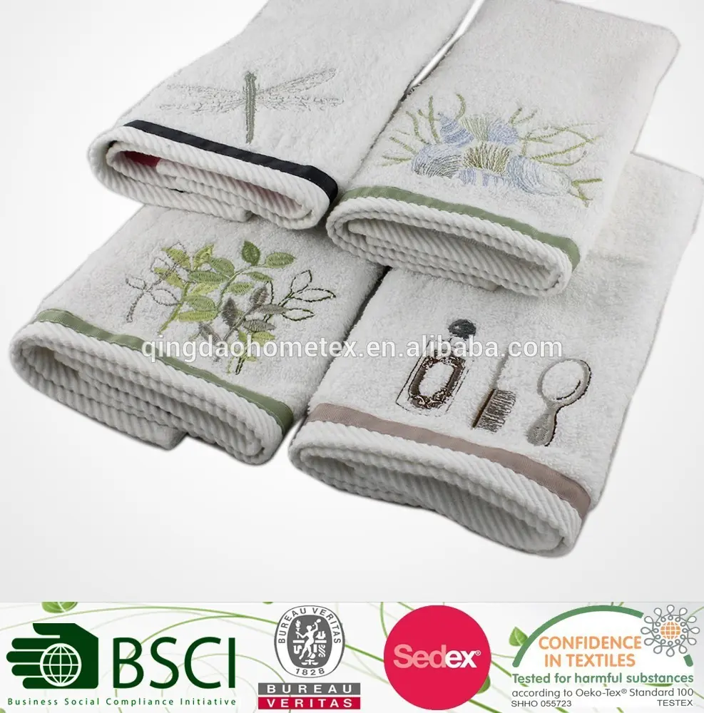 Four folded white towels with embroidered dragonfly, botanical, and toiletry designs on a white background