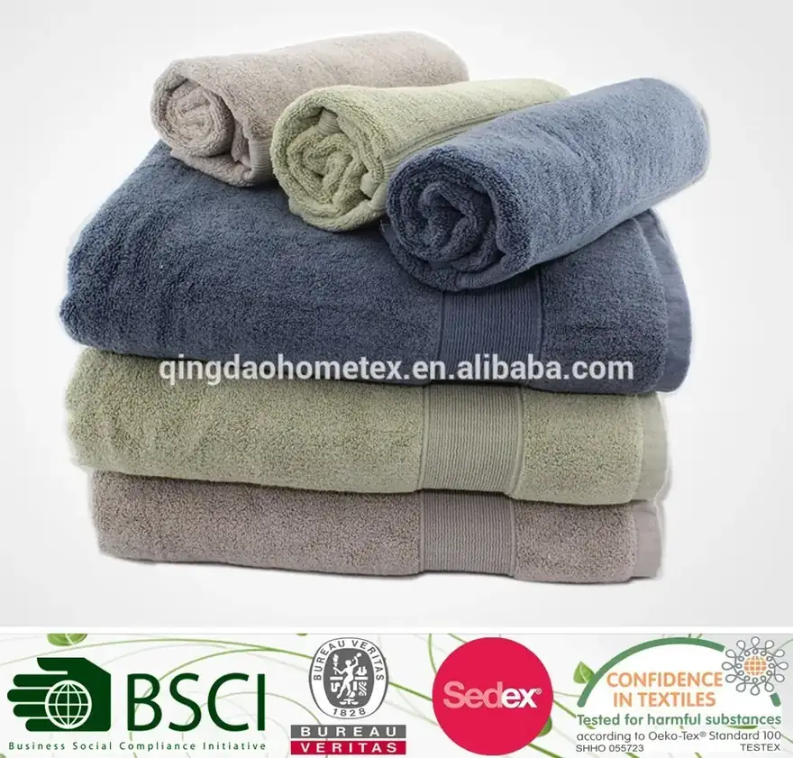 Stack of folded towels in blue, green, and grey with three rolled towels on top