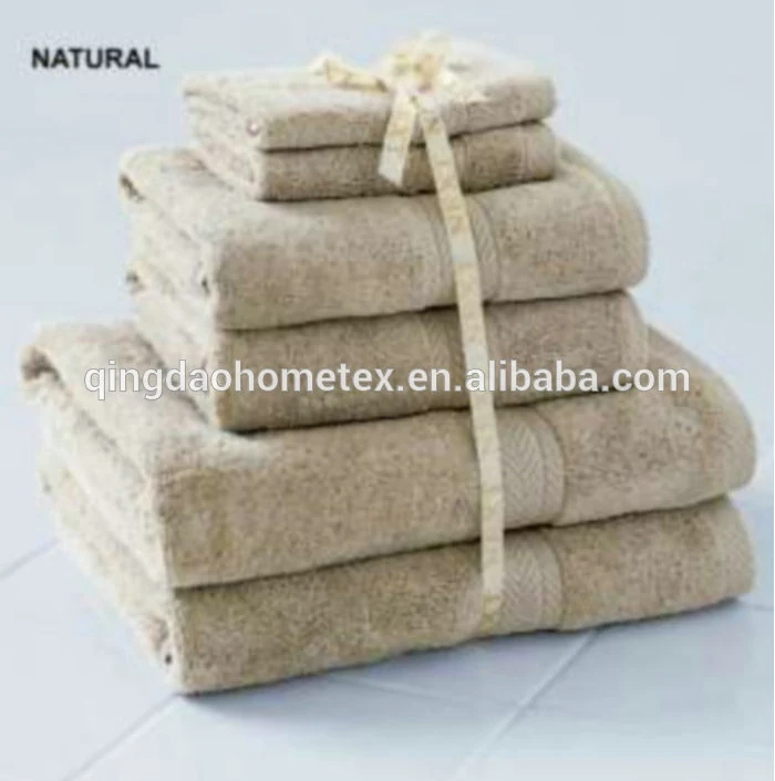 Stack of beige cotton towels tied with a ribbon, on a white tiled surface