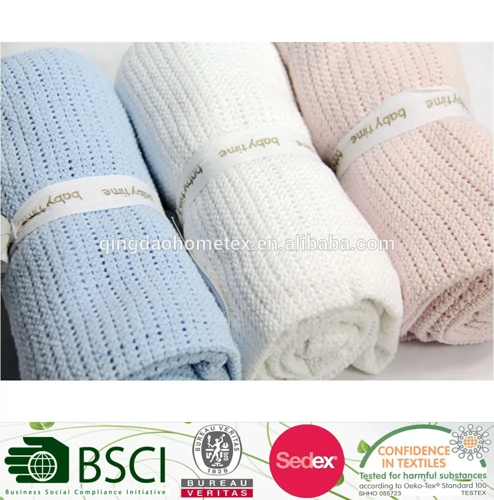 Three rolled knitted baby blankets in blue, white, and pink with paper bands, plus certification logos below