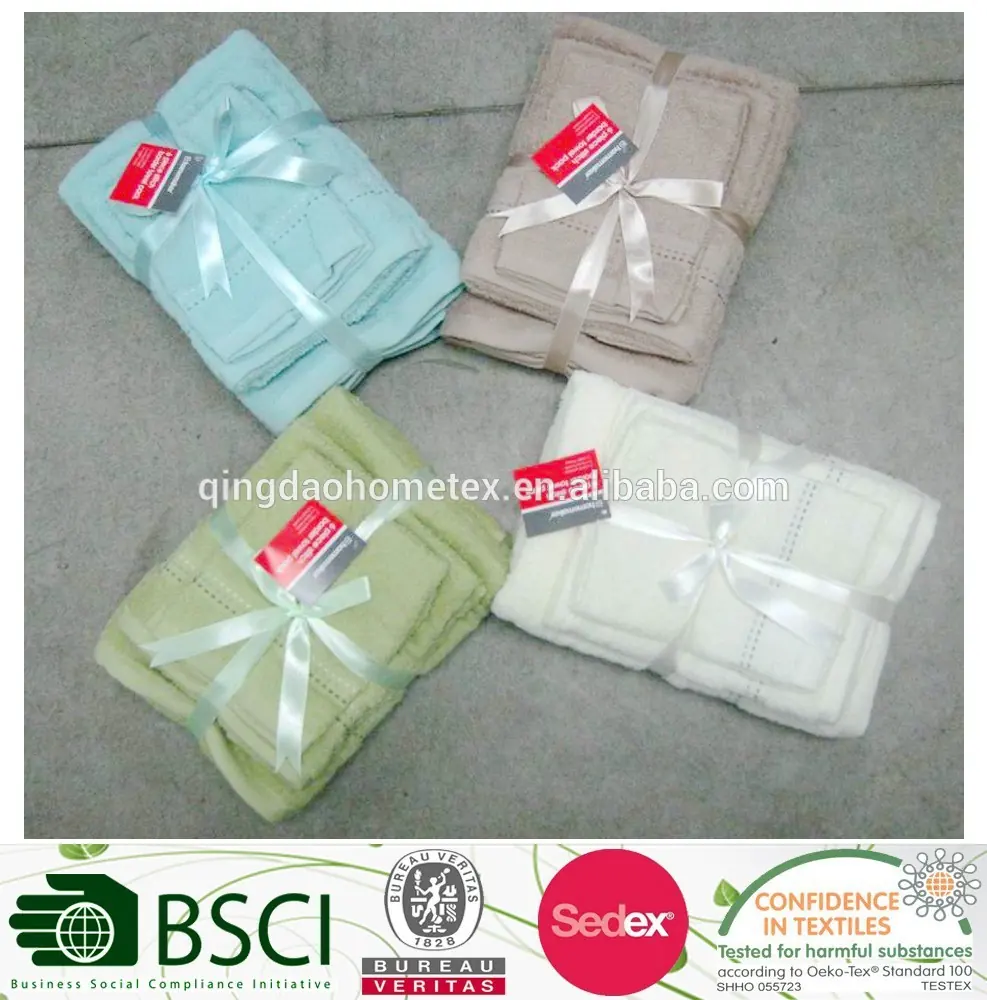 Four sets of folded embroidered towels in pastel colors, each tied with ribbon and tags, on a concrete floor