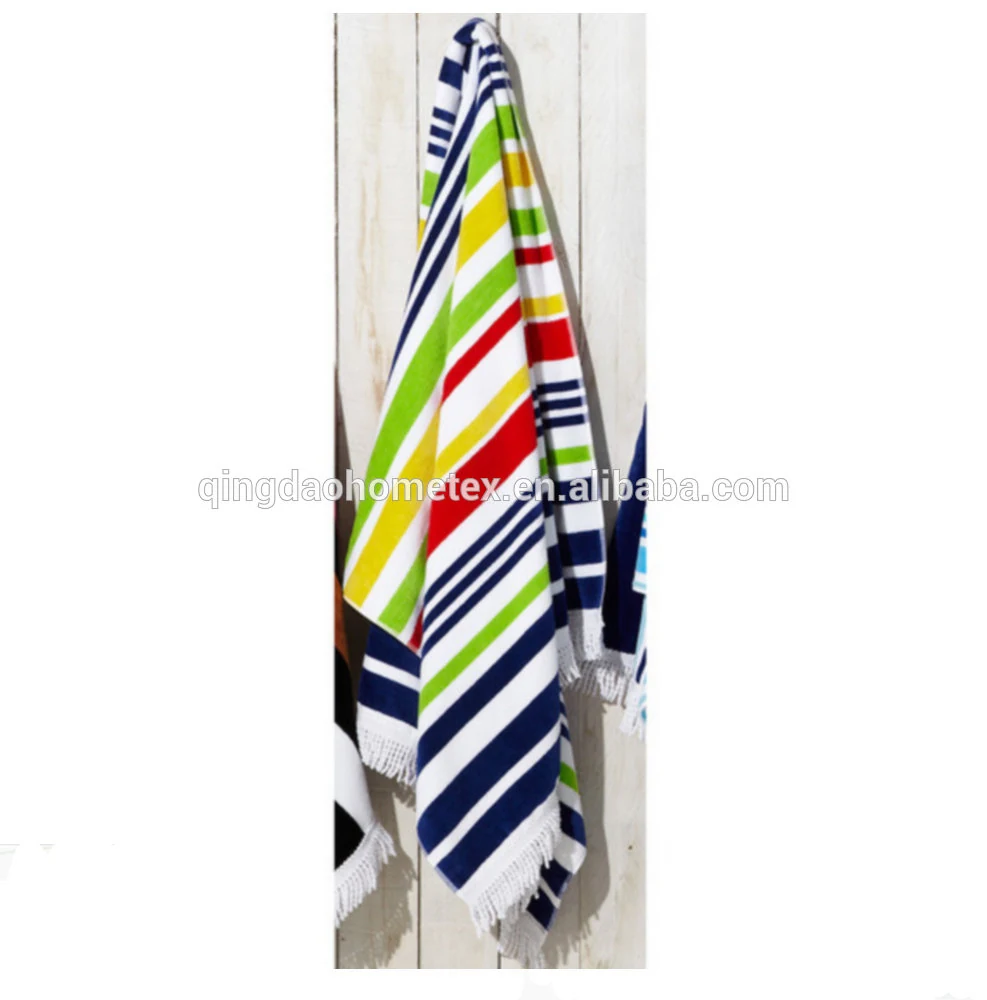 Colorful striped beach towels with fringed edges hanging on a white wooden wall