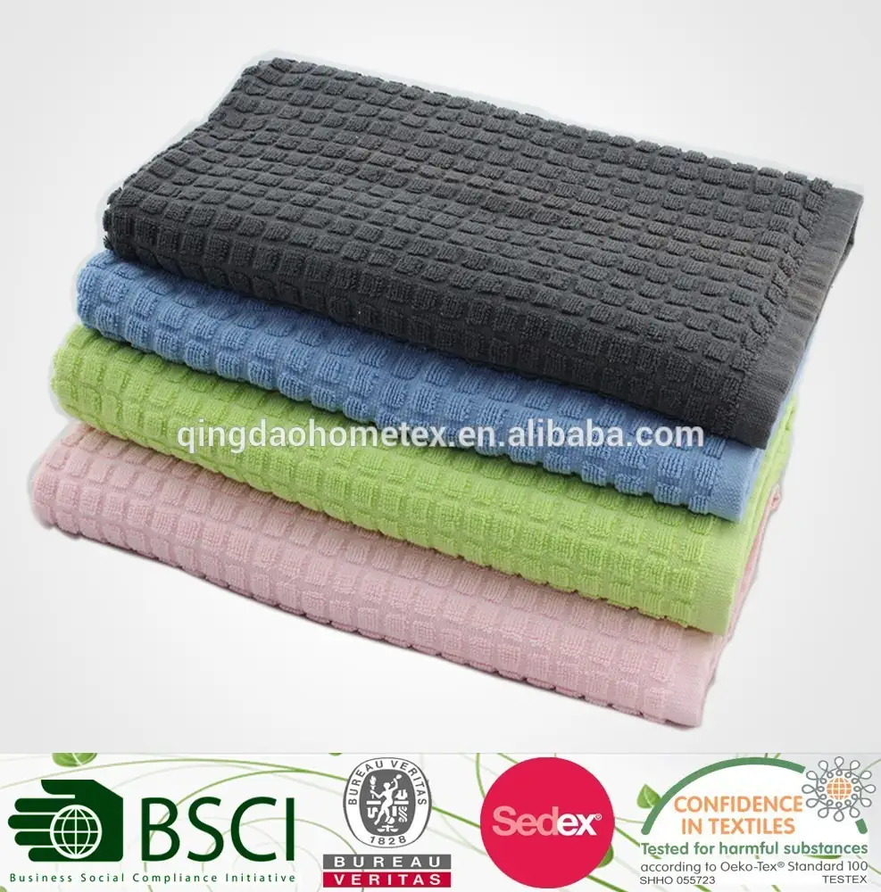 Stack of four folded waffle-weave kitchen towels in gray, blue, green, and pink on a white background