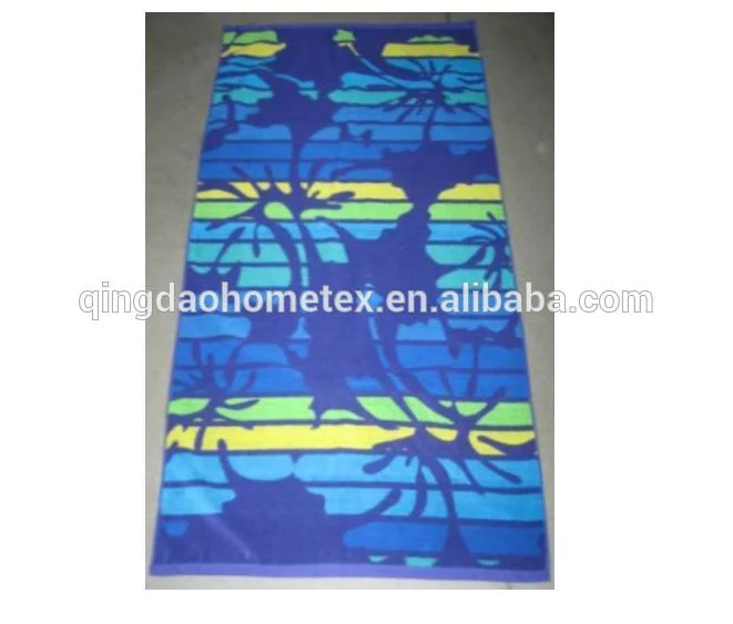 Rectangular beach towel with blue, green, and yellow floral stripe pattern lying flat on a gray floor