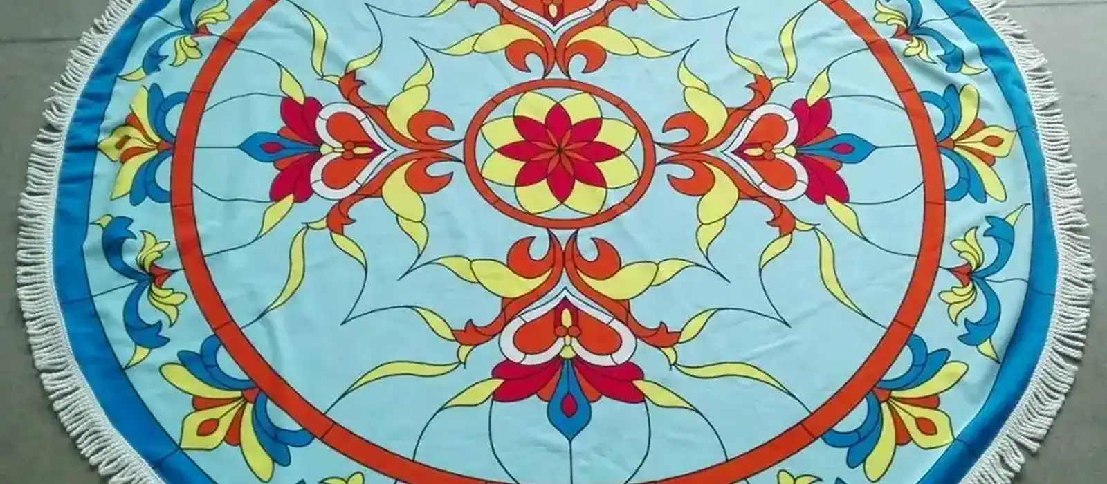 Round cotton beach towel with a printed mandala design and tasselled edge