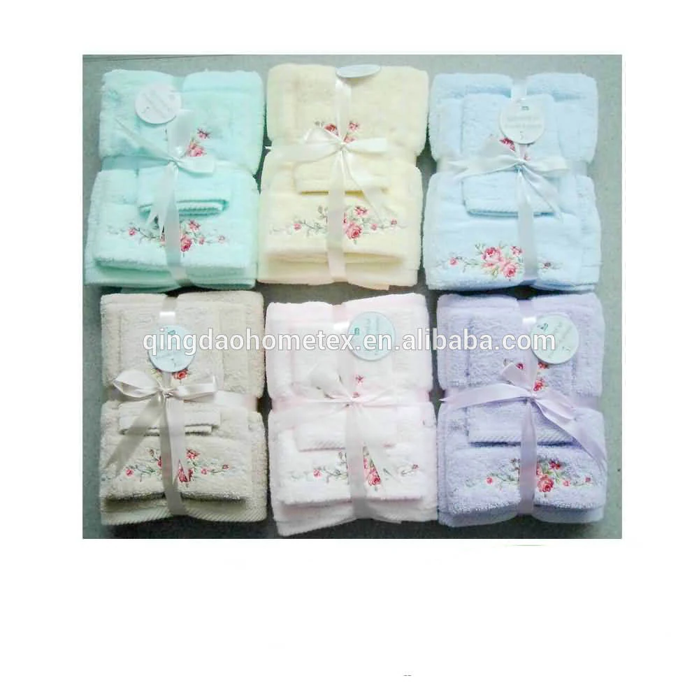 Six pastel embroidered towel sets in green, cream, blue, beige, pink and lavender, tied with ribbons