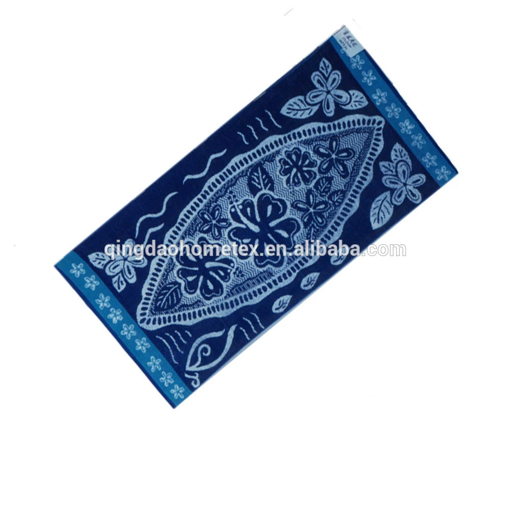 Navy blue beach towel with white and light blue floral batik-style pattern, shown diagonally on a white background