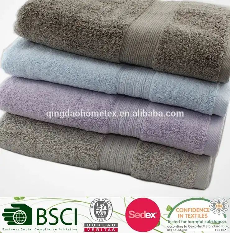 Stack of folded terry towels in grey, blue, and lavender on a white background