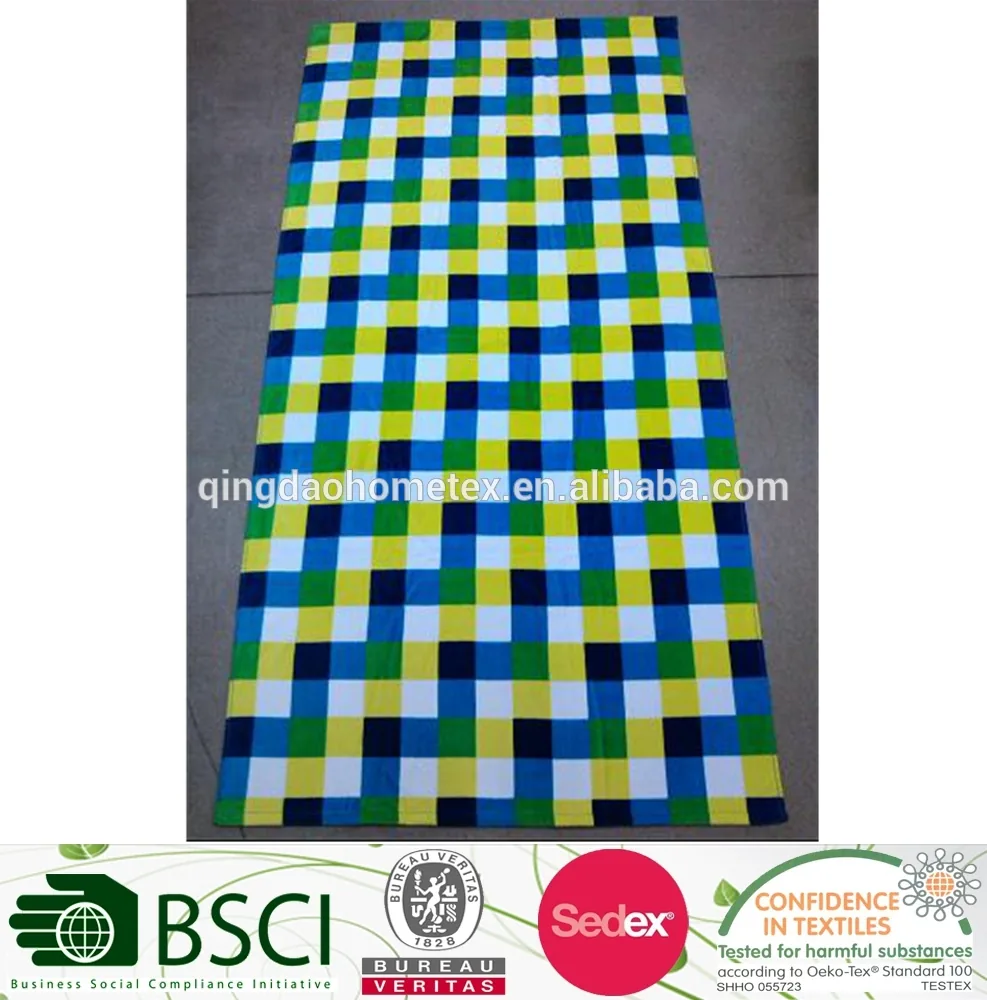 Checkered beach towel in blue, green, yellow and white laid flat on a gray floor