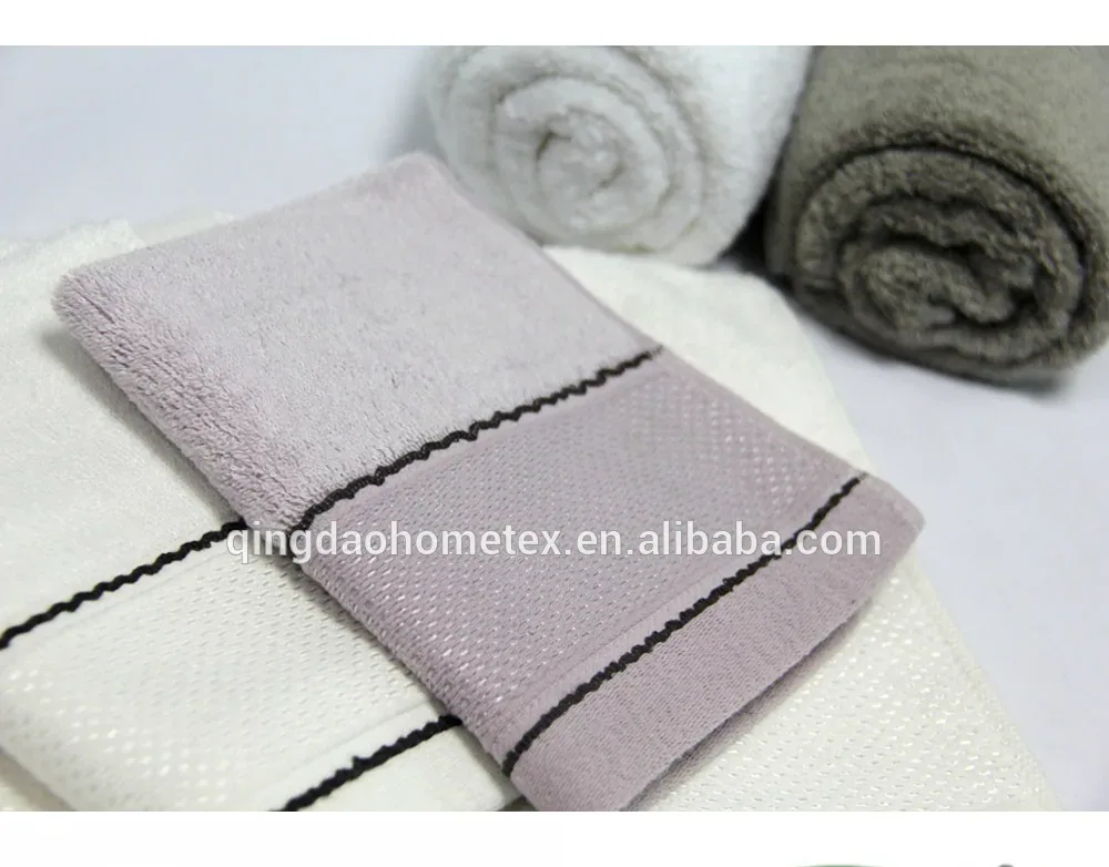 Folded gray and white towels with rolled towels in background, with BSCI and Confidence in Textiles certification logos below.