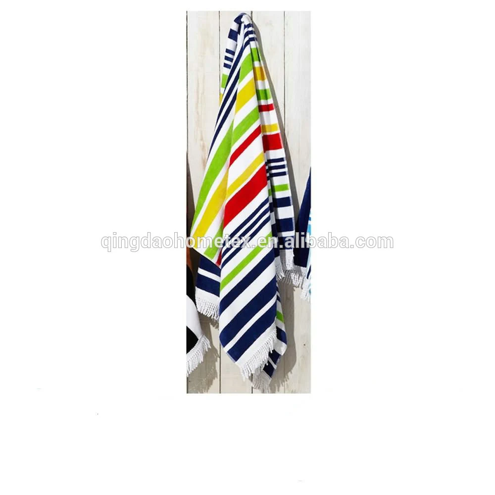 Colorful striped beach towels with fringed edges hanging on a white wooden wall