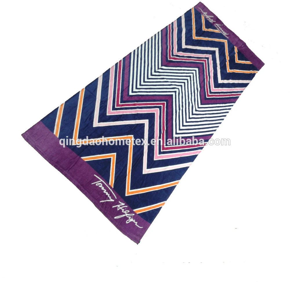 Chevron-striped beach towel in navy, purple, orange and pink with purple borders, laid diagonally on a white background
