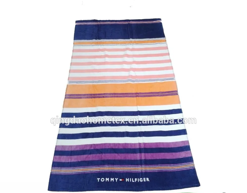 Striped beach towel in navy, pink, orange and purple with Tommy Hilfiger branding on a white background