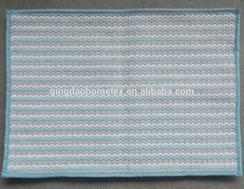 Woven mat with blue, grey and white zigzag stripes and light blue border on grey surface