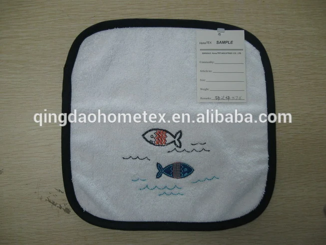 White embroidered towel with two colorful fish designs and black trim, sample tag attached