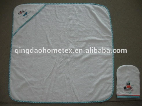 White baby hooded towel with embroidered fish and boat details and matching wash mitt on grey background