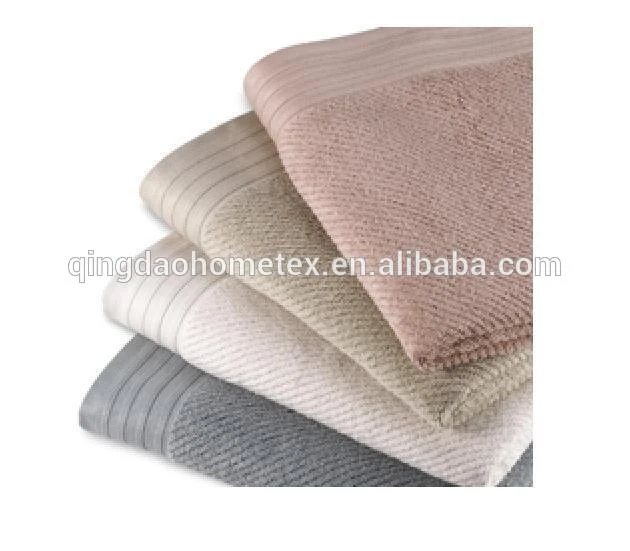 Stack of folded cotton towels in pink, beige, cream, and grey on a white background