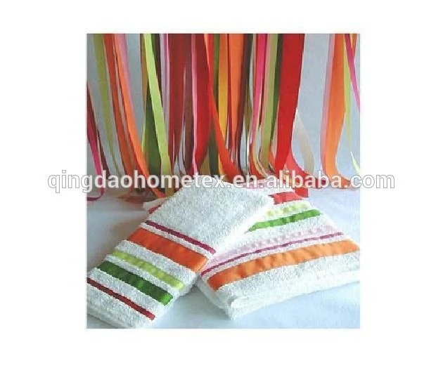 Folded white towels with colorful stripes and ribbon borders, colorful ribbons hanging in the background