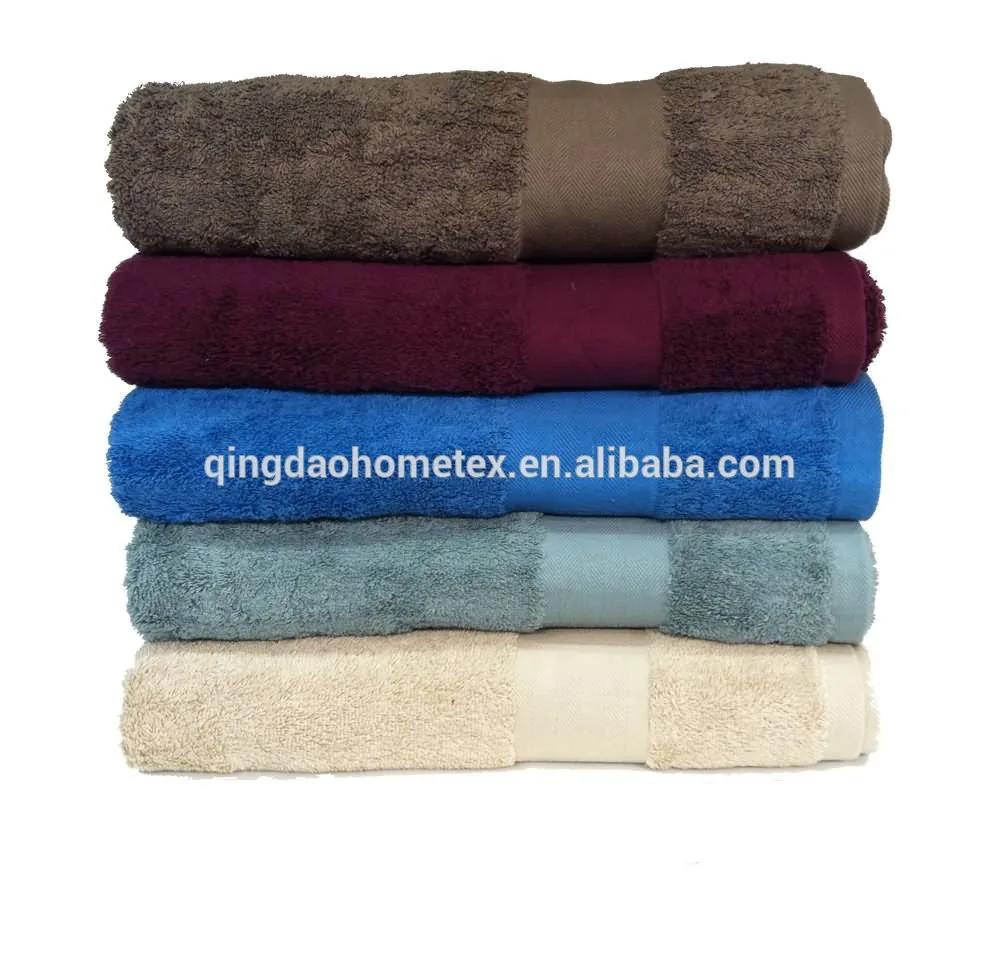 Stack of five folded towels in brown, burgundy, blue, light blue, and beige on a white background