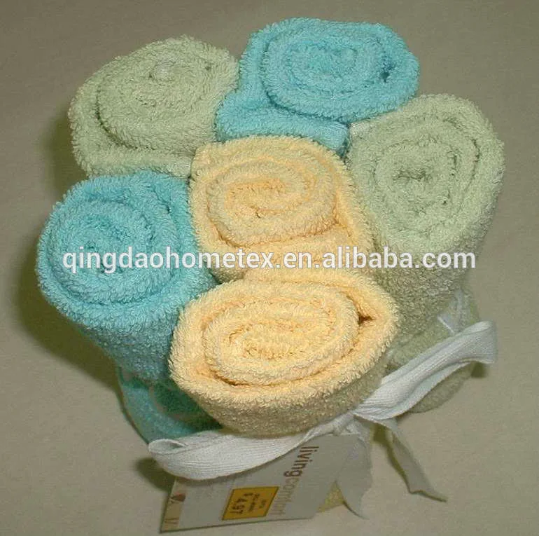 Rolled towels in pastel blue, green and yellow arranged in a flower shape and tied with a white ribbon