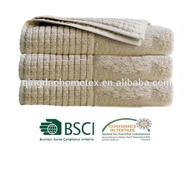 Stack of folded beige towels with waffle weave bands on white background