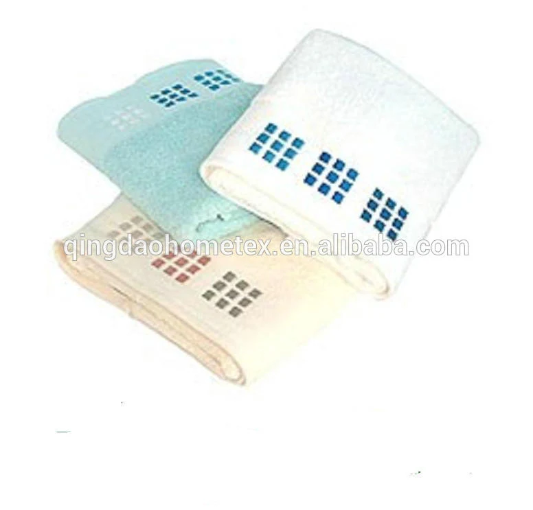 Three folded towels in white, light blue, and cream with blue and red square-pattern borders on a white background