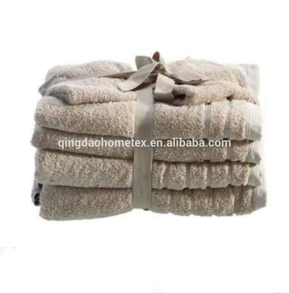 Stack of folded beige towels tied with a ribbon against a white background