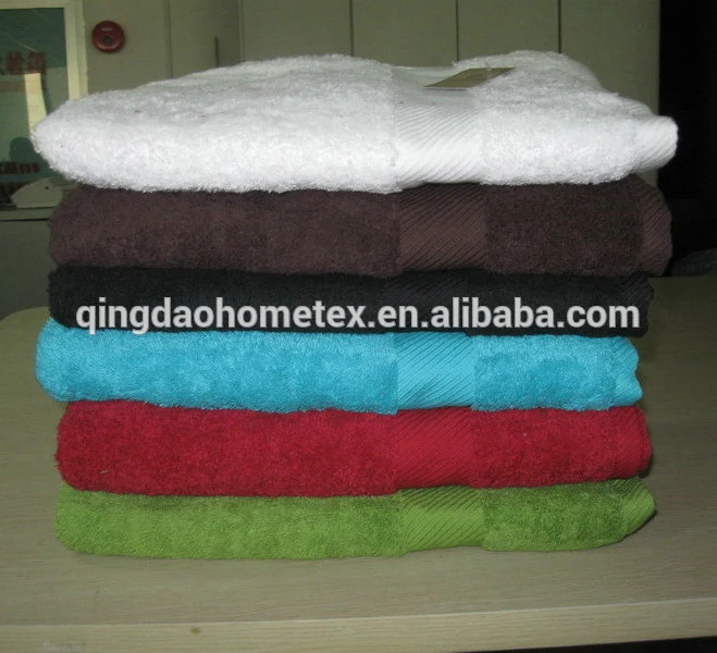 Stack of folded terry towels in white, brown, black, turquoise, red, and green on a table