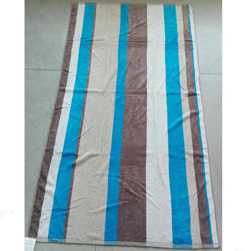 Striped beige, brown, and blue woven mat or rug laid flat on a grey tiled floor.