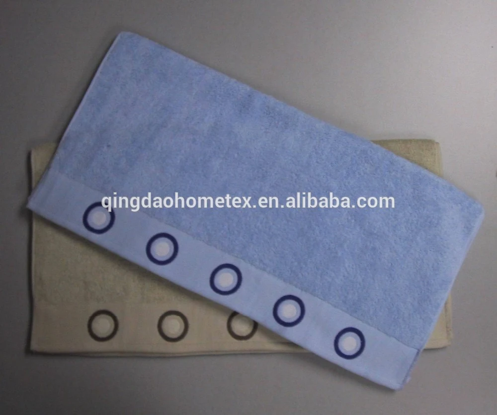 Blue and beige terry towels with embroidered ring borders stacked on a grey surface