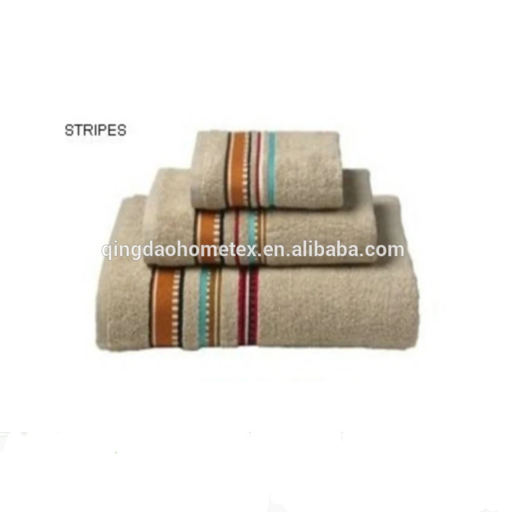 Stack of beige towels with orange, teal and striped borders on a white background