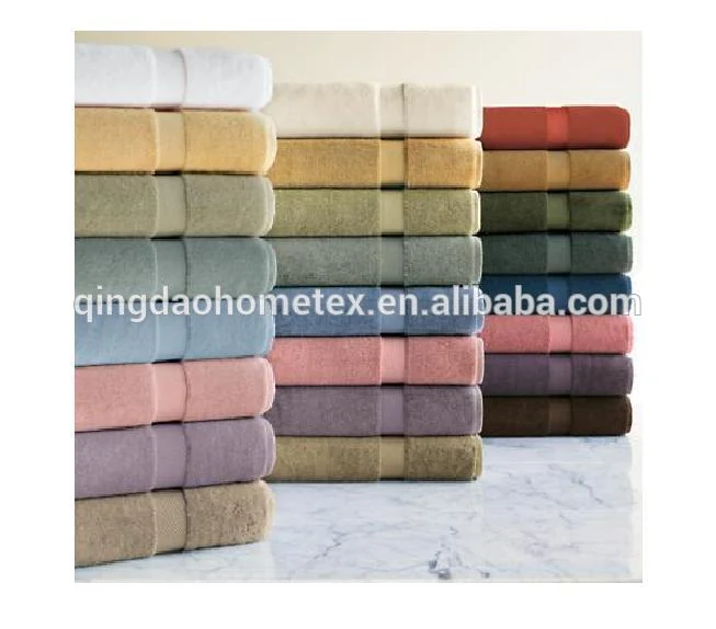 Stacks of folded towels in various colors arranged on a marble surface.