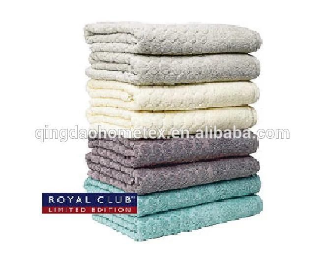 Stack of folded towels in gray, cream, purple, and teal colors on a white background