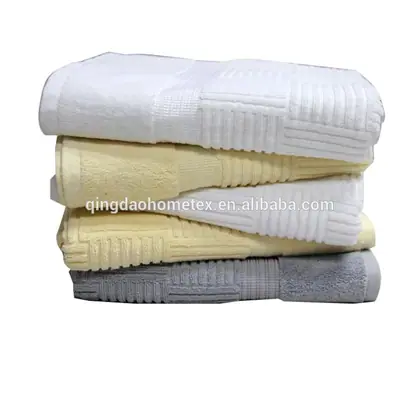 Stack of folded bath towels in white, cream, and gray on a white background