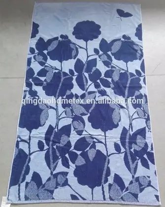 Light blue towel with large blue floral print and butterfly motif, laid flat on a grey floor