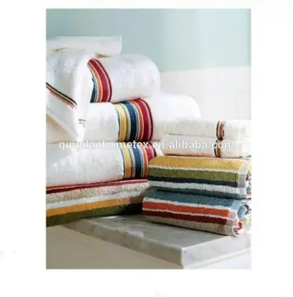 Stack of folded white towels with colorful striped borders on a marble surface against a pale blue wall